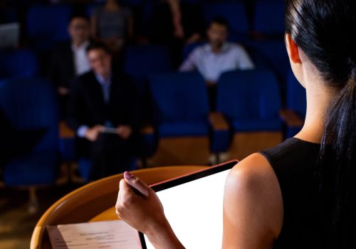 Rear view of female business executive giving a speech at conference center